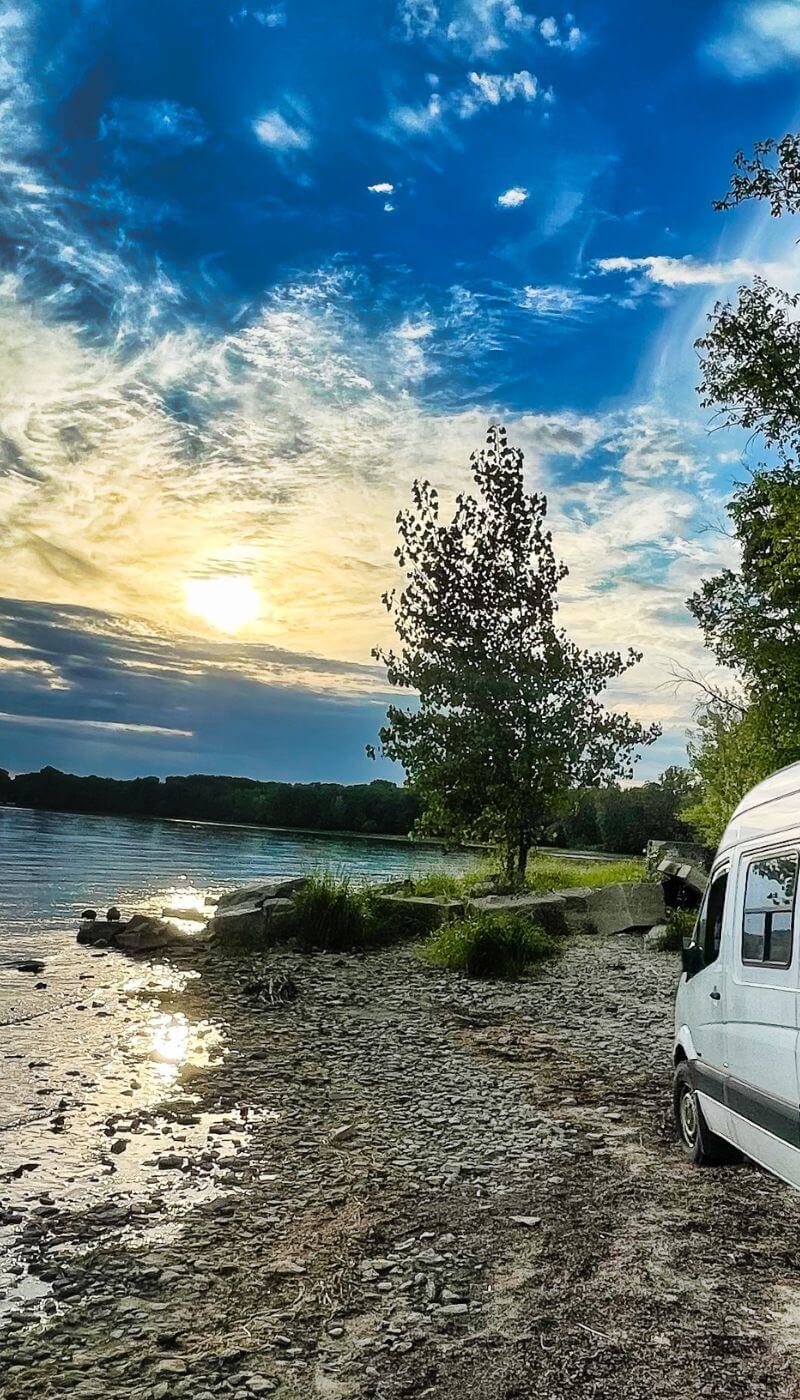 Lonavity van parked by the Gatineau River beach, beautiful sunset, Vanlife